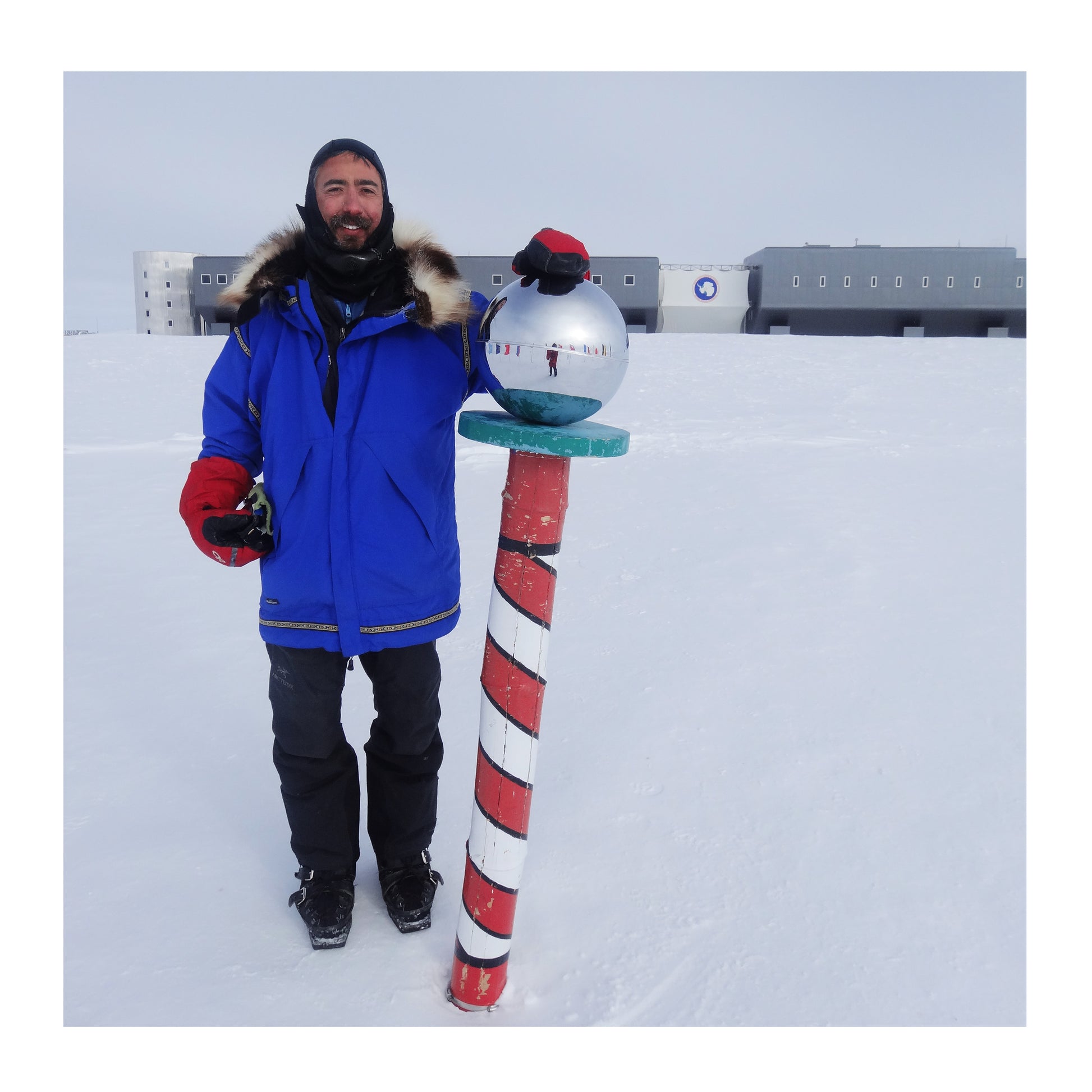 Aaron R. Linsdau standing at the South Pole, Antarctica